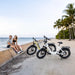 A couple parked their kingbull electric bikes next to rest by the sea