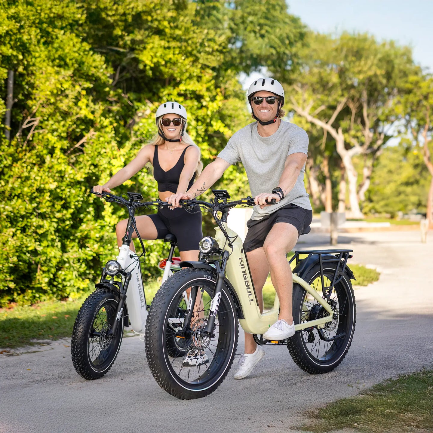 A couple riding their kingbull electric bicycles in the park with bright smiles